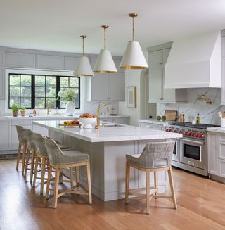 kitchen with gray island topped with white worktop white cabinets white pendant lights andwith steel framed windows