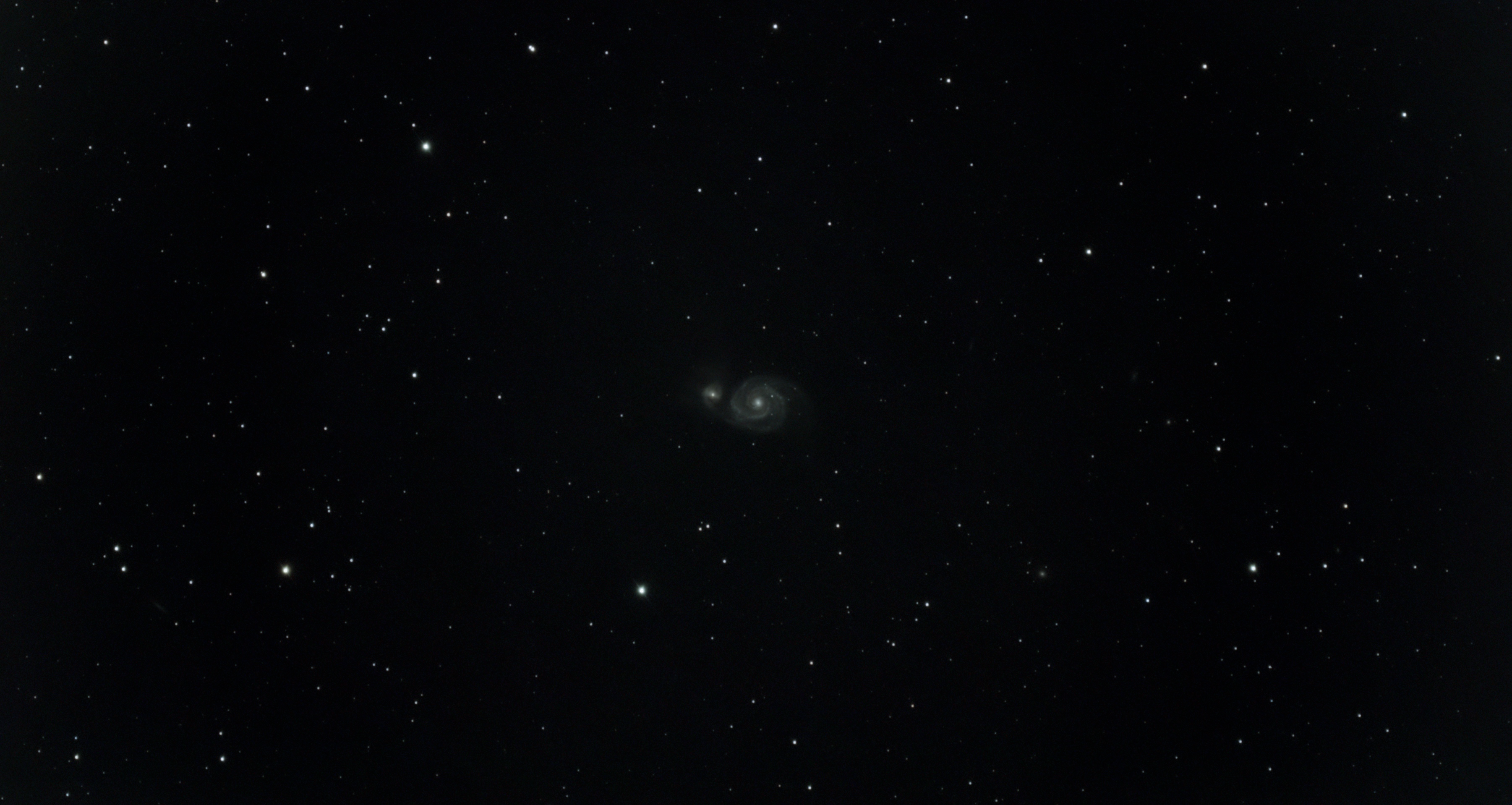 a faint spiral galaxy at the center of the image surrounded by stars.