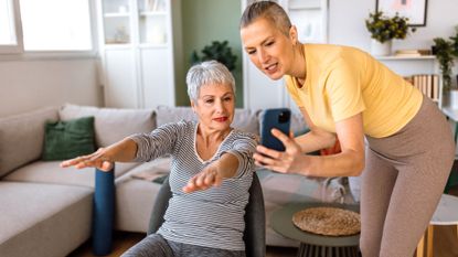 senior woman does seated exercise with trainer