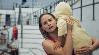 Maddie wet after getting out the pool, holding Theo in a yellow dressing gown in Playing Nice