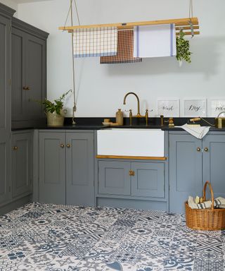 Blue laundry room scheme with patterned floor tiles, blue painted cabinets, and ceiling hung wooden clothes dryer