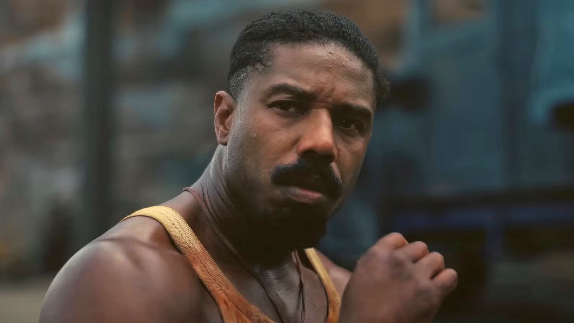 Michael B. Jordan brings his hand to his face as he looks on