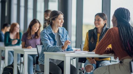 Three female college students sit a table to study together.