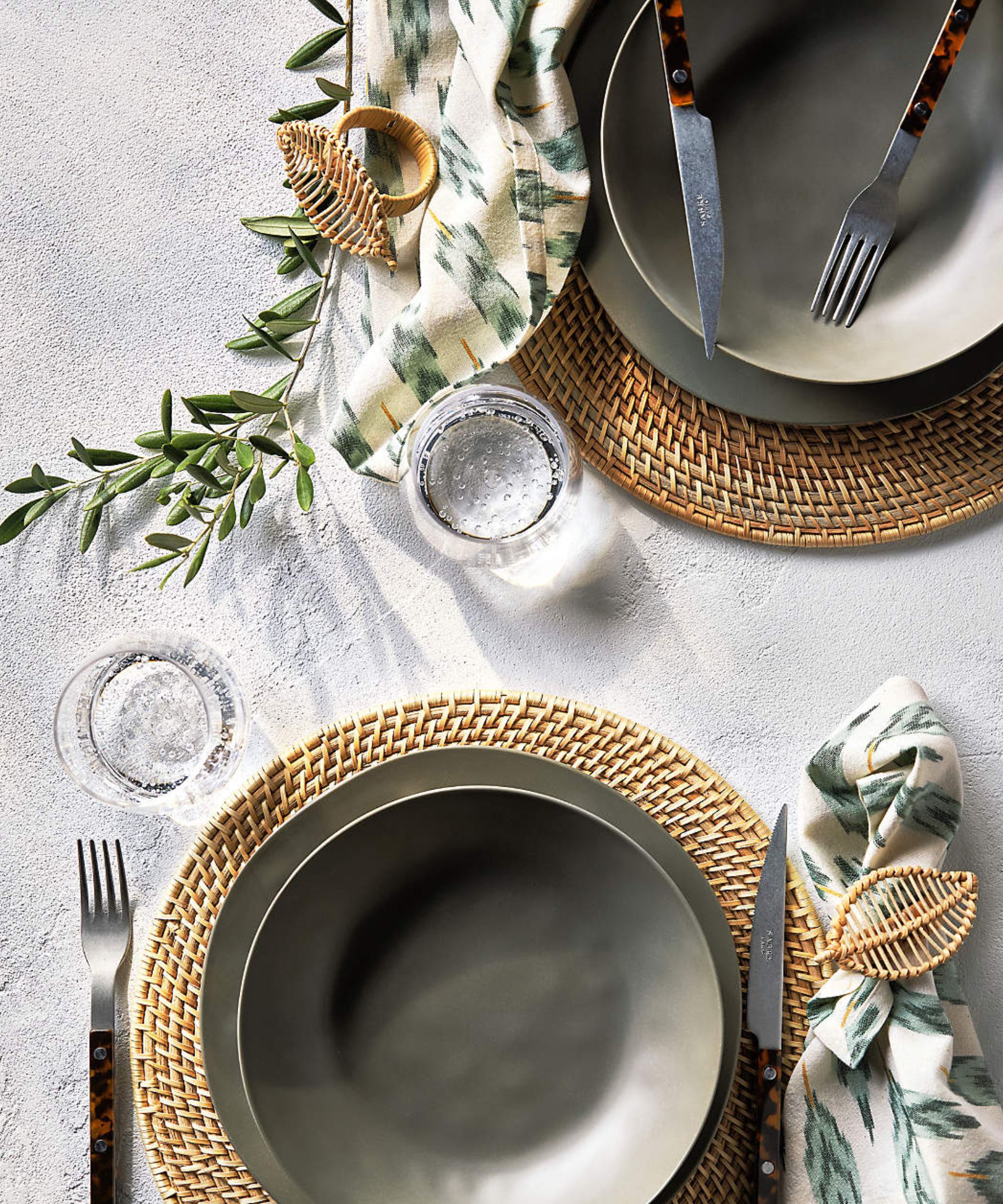 White table setting with olive green plates and rattan placemats