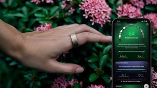 A woman's hand wearing gold Ultrahuman ring in front of greenery and pink flowers overlaid by iphone screen displaying Sleep Cycles data