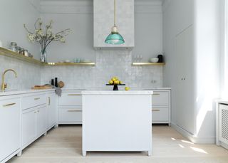 White kitchen with island a green pendant light