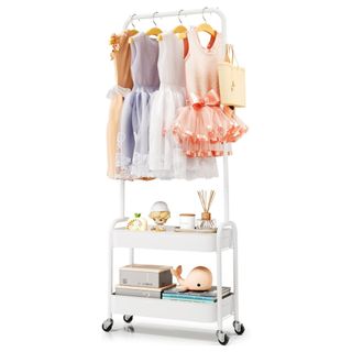 A white kids clothing rack with shelves on wheels with dresses, toys, boxes, books and a diffuser