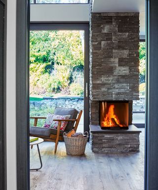 View through a doorway to a lit fire in the Living Room with patio doors to the garden in the background.