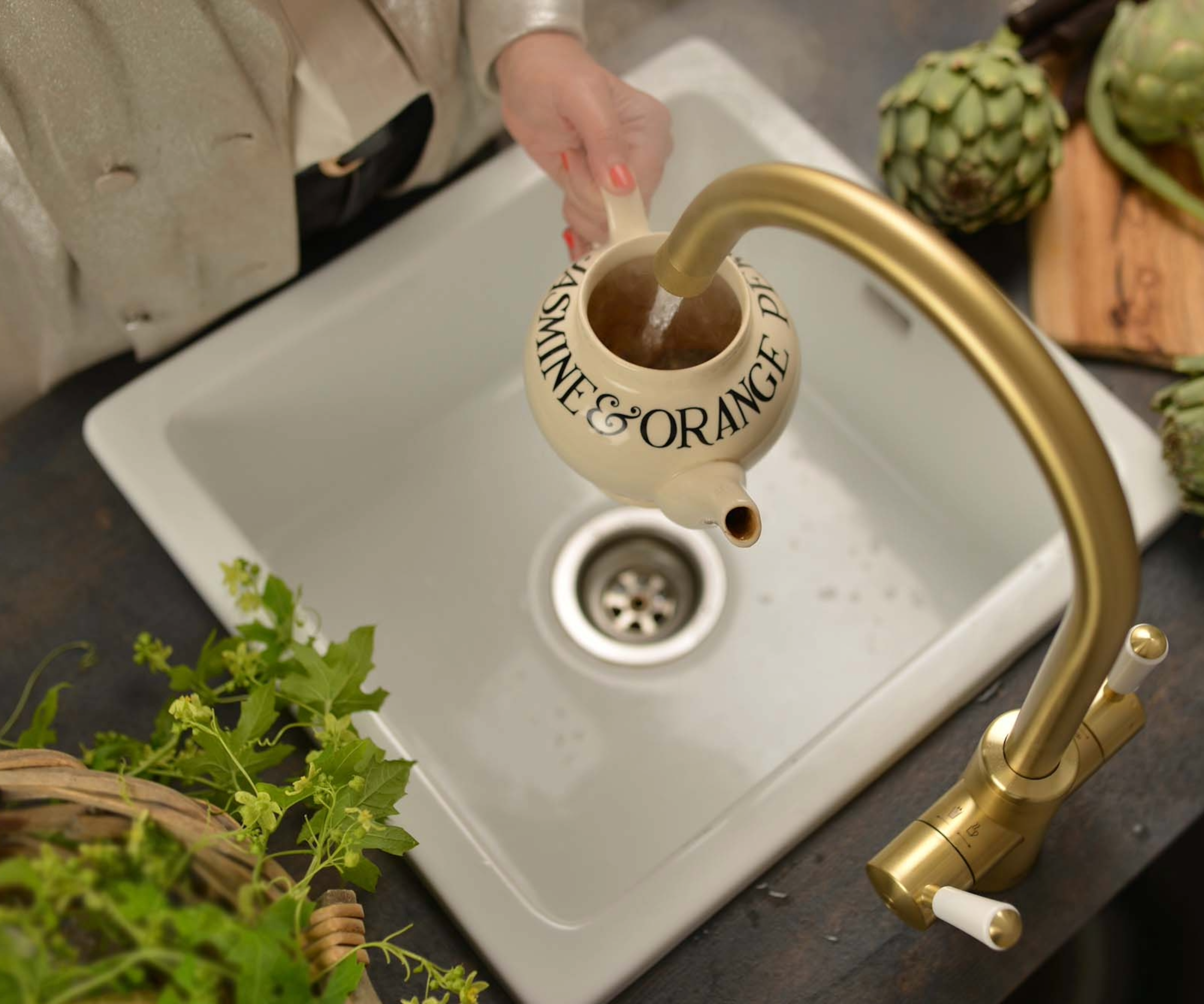 Hand holding a mug underneath a gold tap