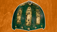 a green-tinted bronze helmet with gold figurines on the front