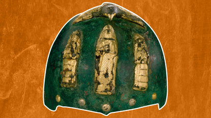 a green-tinted bronze helmet with gold figurines on the front