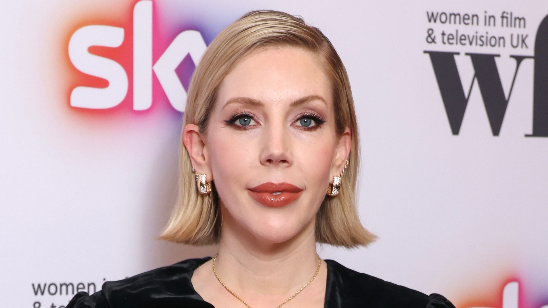 Image of Katherine Ryan smiling with short blonde chin-length bob and wearing gold hoop earrings