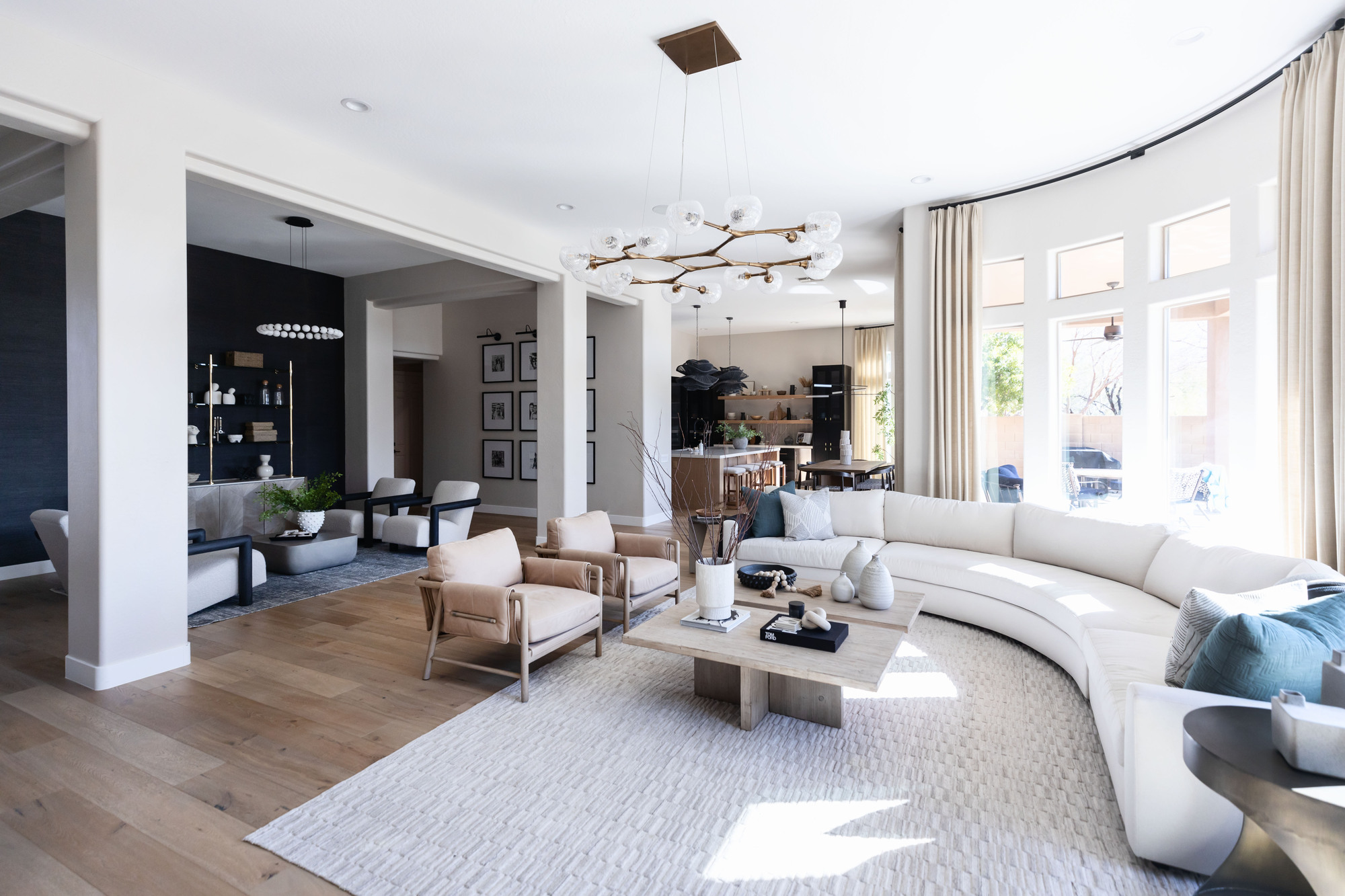 A large living room with a curved sofa, a large rug, and a separate conversation area