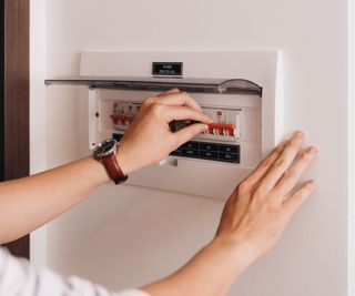 A woman's hands flipping breakers on an indoor transfer switch