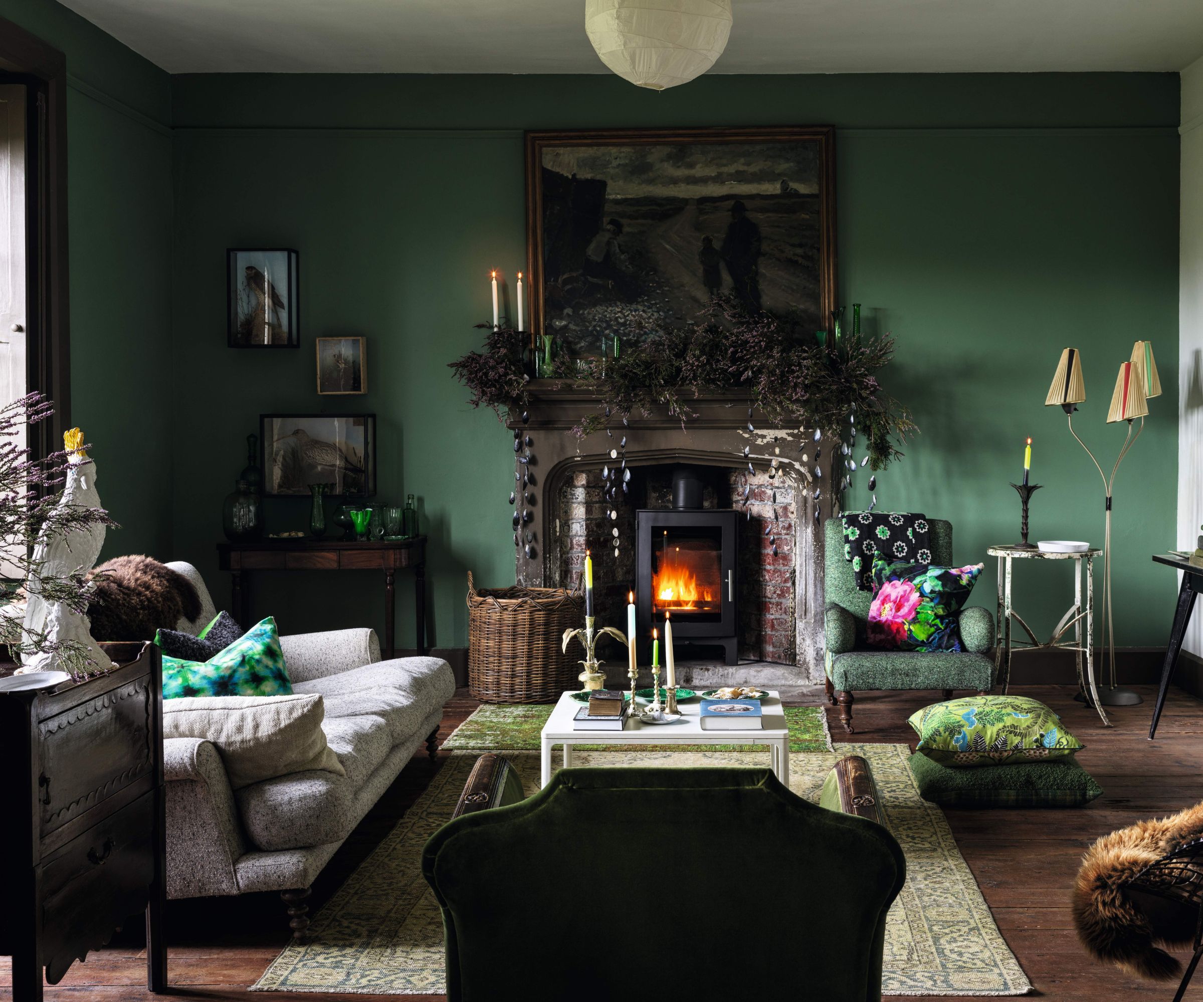 Dark green traditional living room decorated for Christmas with a stone fireplace and garland