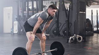 Man standing over a barbell with weight plates on