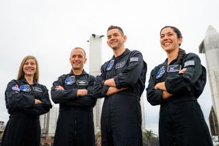 polaris dawn crew members in black jumpsuits pose in front of spacex starship hardware