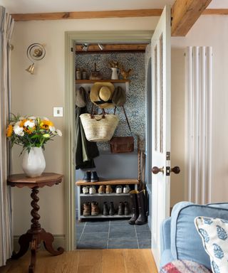 cottage hallway with patterned wallpaper, peg hook and shoe rack