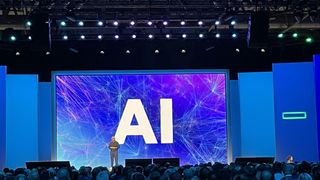 HPE CEO Antonio Neri standing in front of a screen on the keynote stage with AI in giant letters behind him.