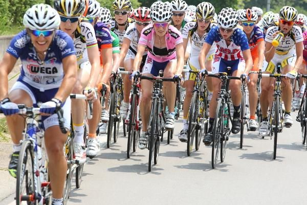 The pink jersey rolls along, surrounded by her teammates.