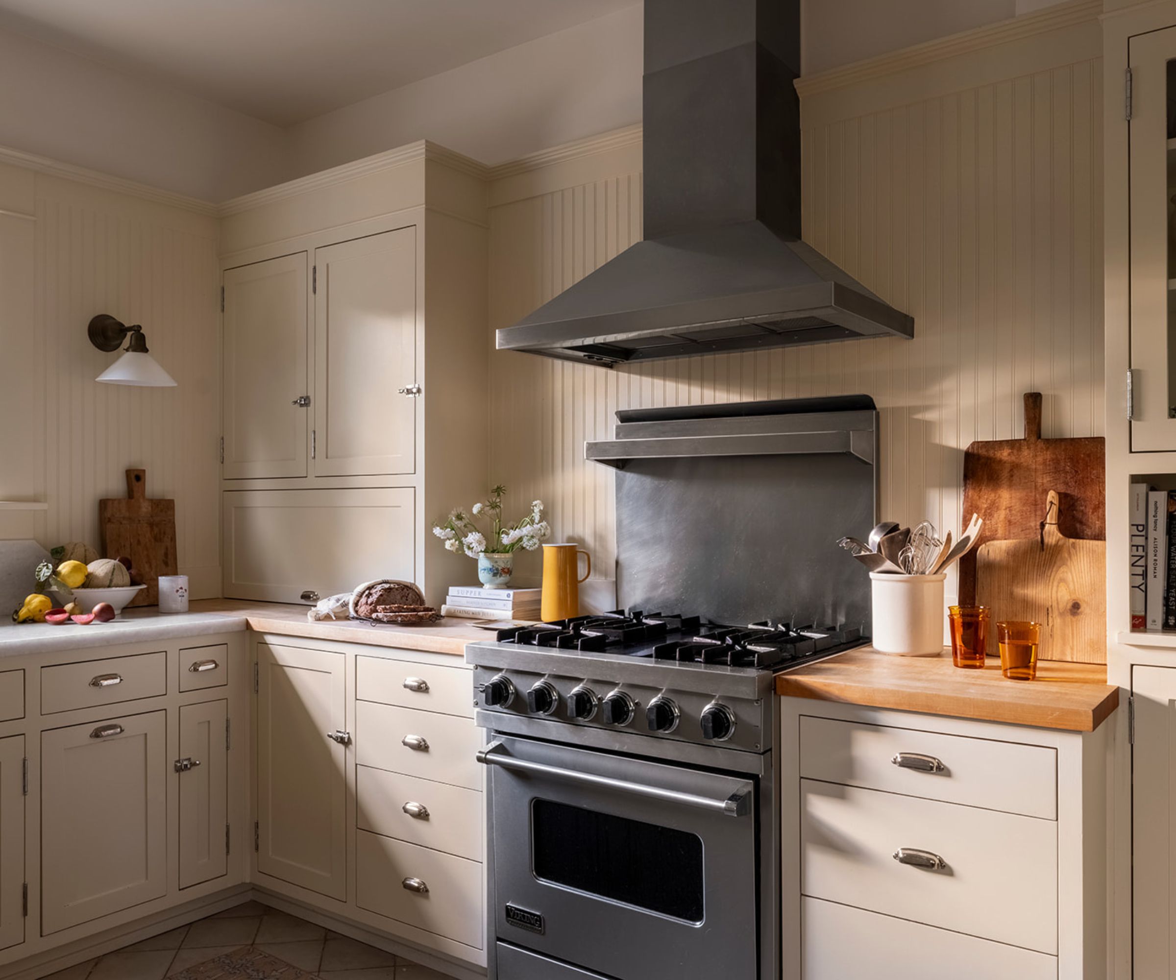 A Craftsman kitchen with neutral cabinets, a paneled backsplash, and stainless steel appliances