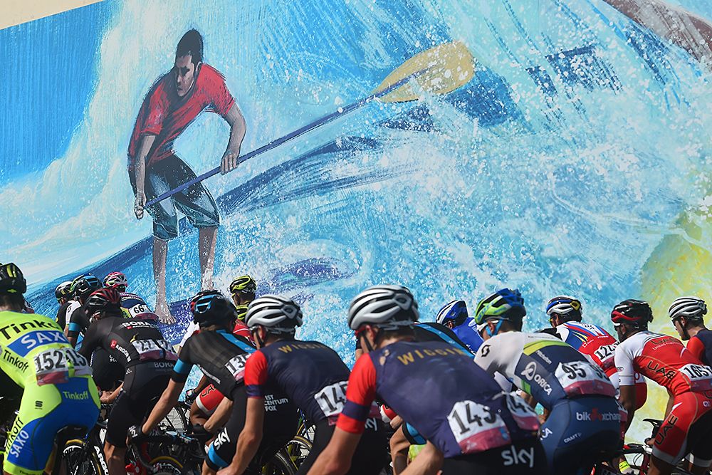 The peloton passes a mural Abu Dhabi Tour