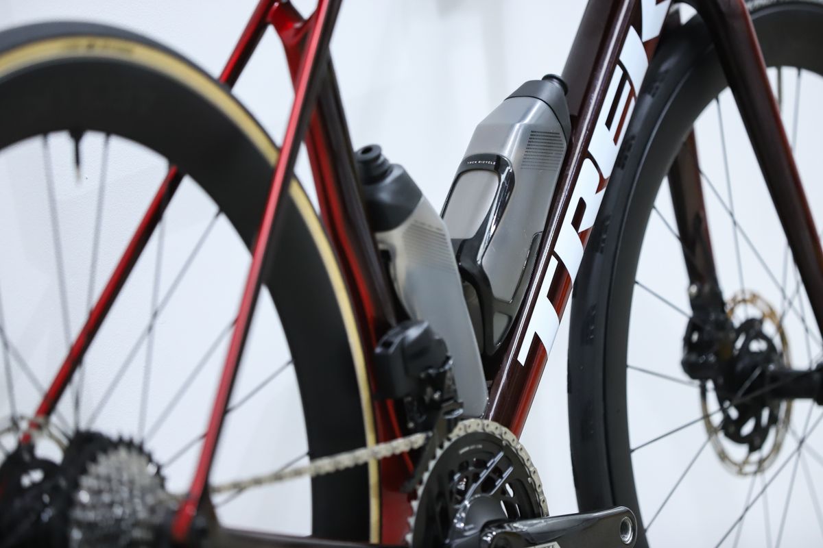 A red Trek Madone SLR 7 (gen 8) stands against a white wall