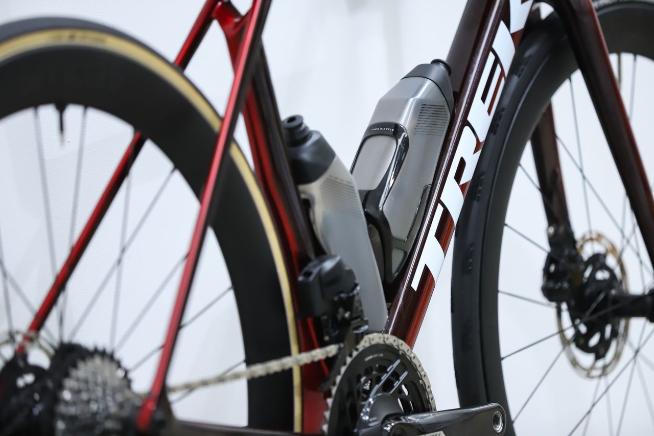 A red Trek Madone SLR 7 (gen 8) stands against a white wall