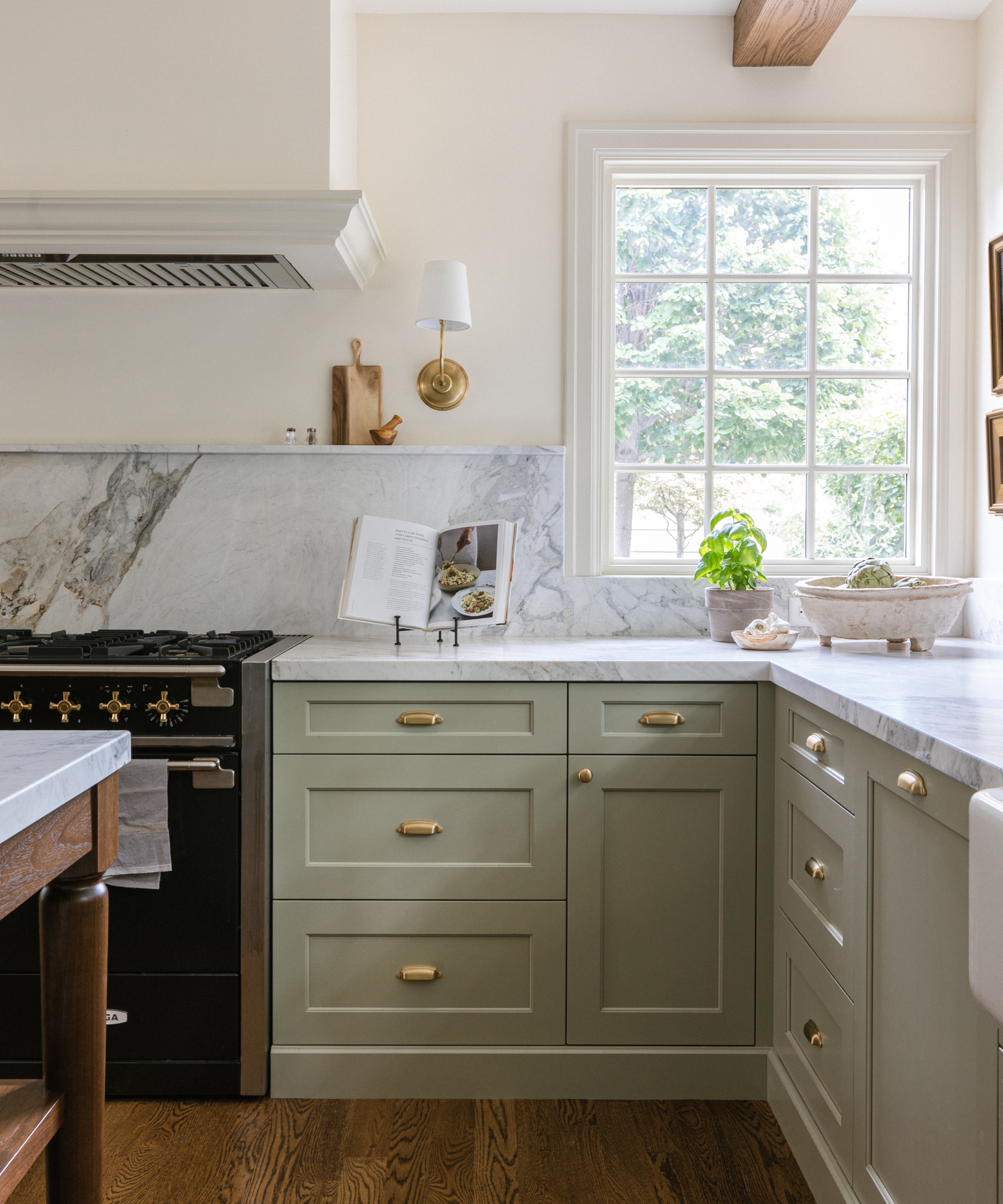 A timeless kitchen with marble countertops, white walls, and cabinetry painted in French Gray by Farrow &amp;amp; Ball