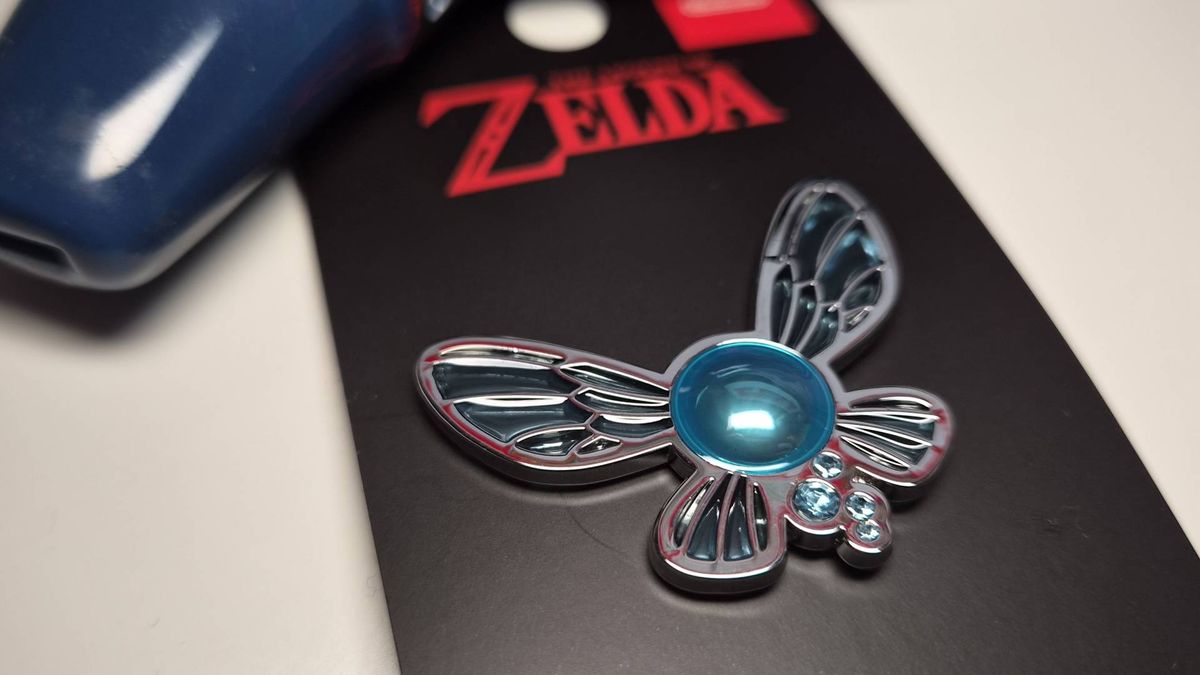 Photo of the Legend of Zelda Fairy pin sitting on its black backing packaging.