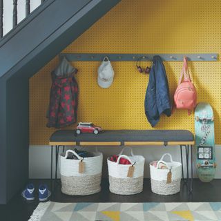 Under-stairs nook with a bench, storage baskets and children's coats