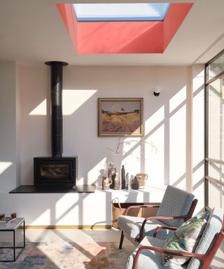 sun room living room with chairs and a log burner fire and a red painted ceiling light window