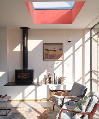 The sunroom living room has seating, a wood-burning fireplace and a red-painted skylight in the ceiling.