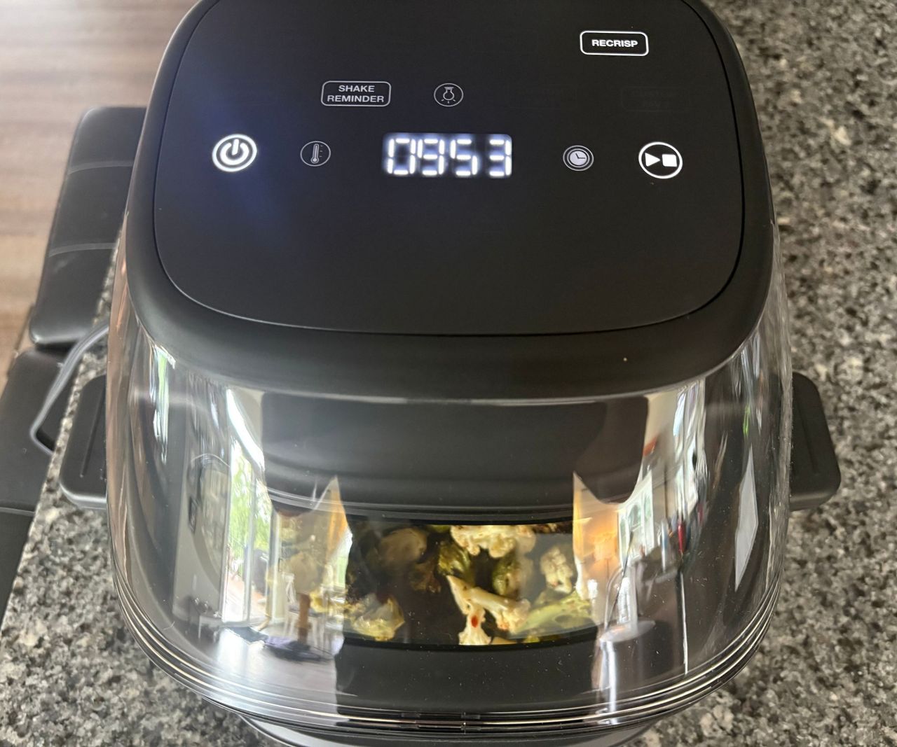 The Cuisinart glass air fryer on a granite countertop frying vegetables.