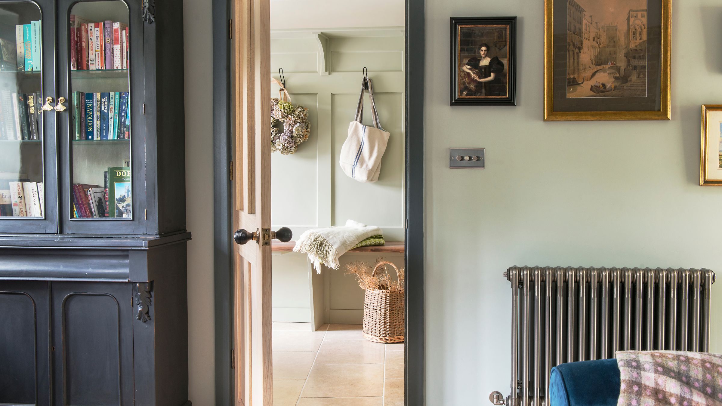Country-style living room looking out into a hallway with green panelling and hooks for bags and coats on the wall