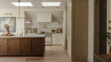 A large kitchen with cream painted cabinets and a large wooden cabinet island. 