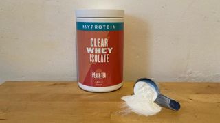 Tub of MyProtein Clear Whey Isolate on a table with some powder dispensed