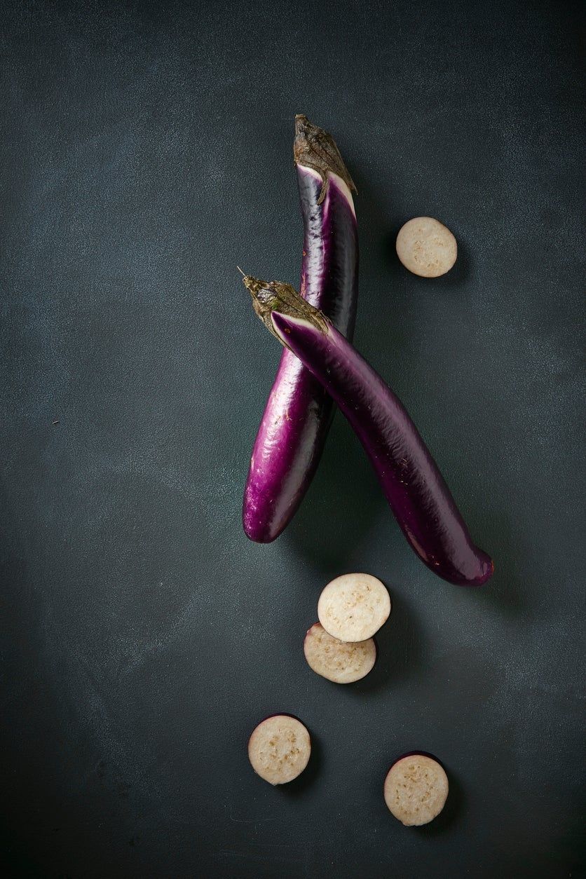 Two Whole Japanese Eggplants Next To Slices Of Japanese Eggplants