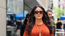 A HEADSHOT OF SALMA HAYEK WEARING AN ORANGE DRESS AND SUNGLASSES