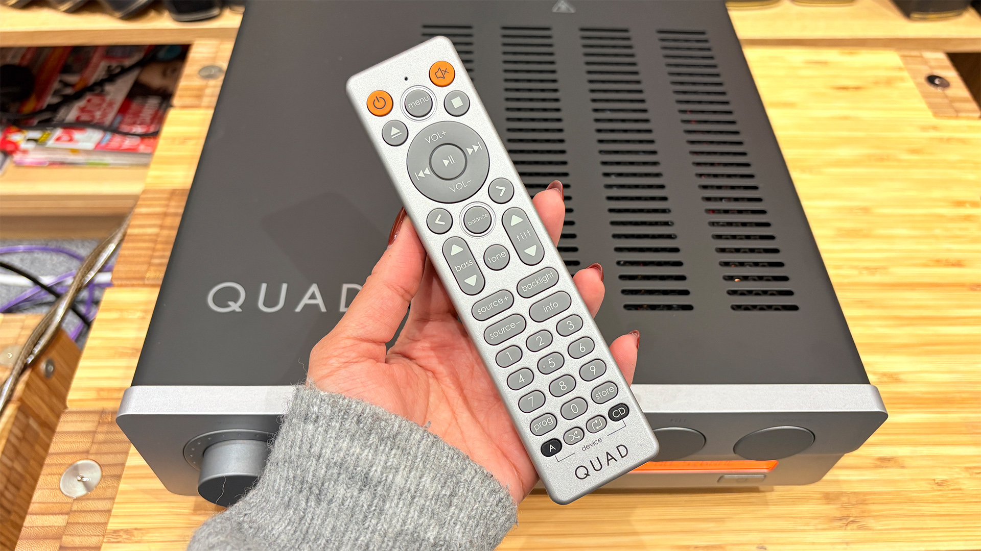 Quad 3 integrated amplifier with remote control held in hand above