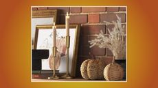 target thanksgiving decor including a woven pumpkin, candles, and a pumpkin picture on a mantle and an exposed brick wall in the back