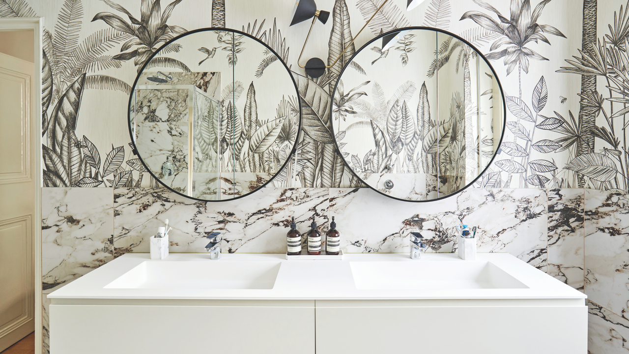 Double bathroom tap and mirror with circular mirrors and statement wallpaper.