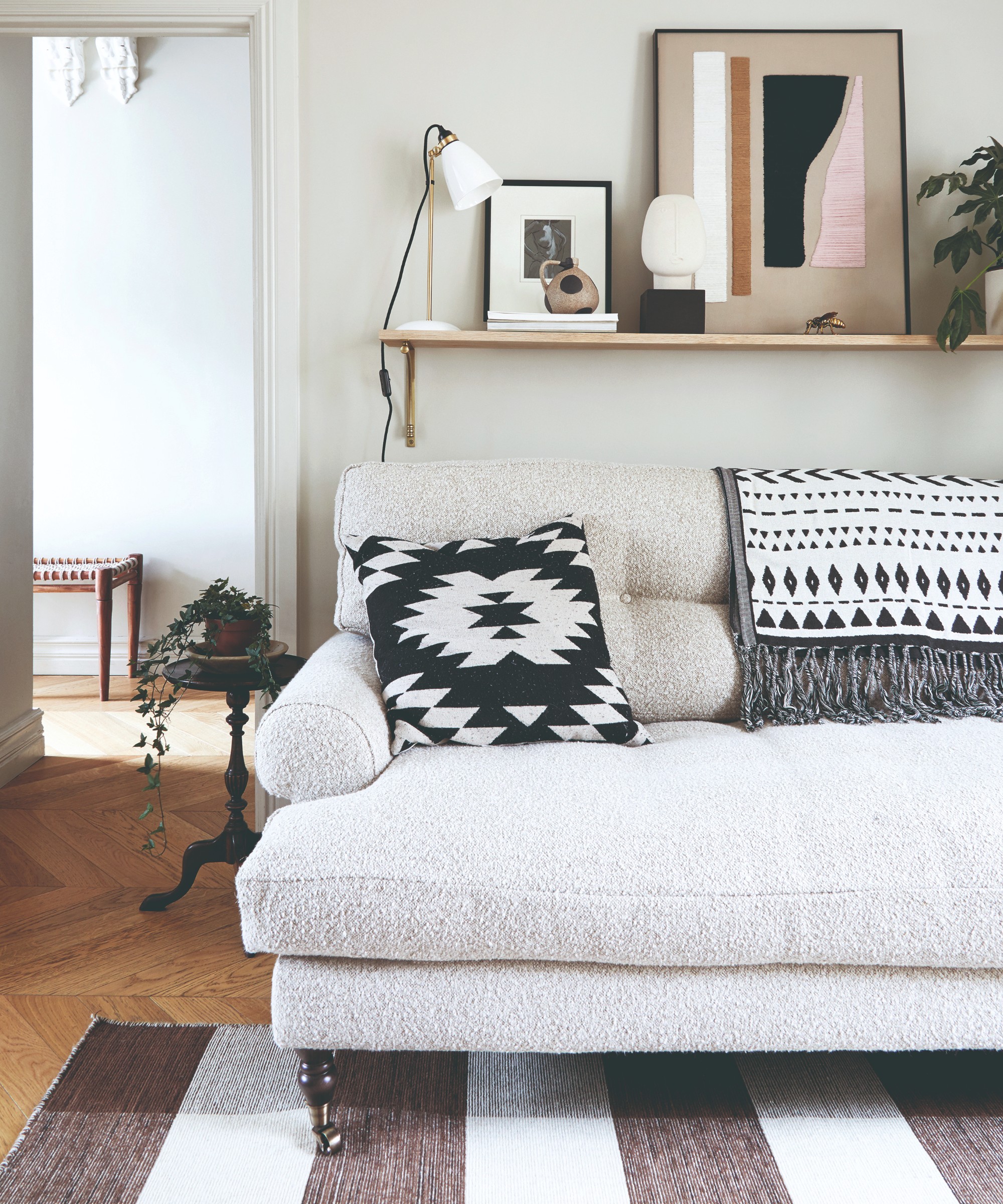 An off white-painted living room with a cream boucle sofa and a striped black and white rug