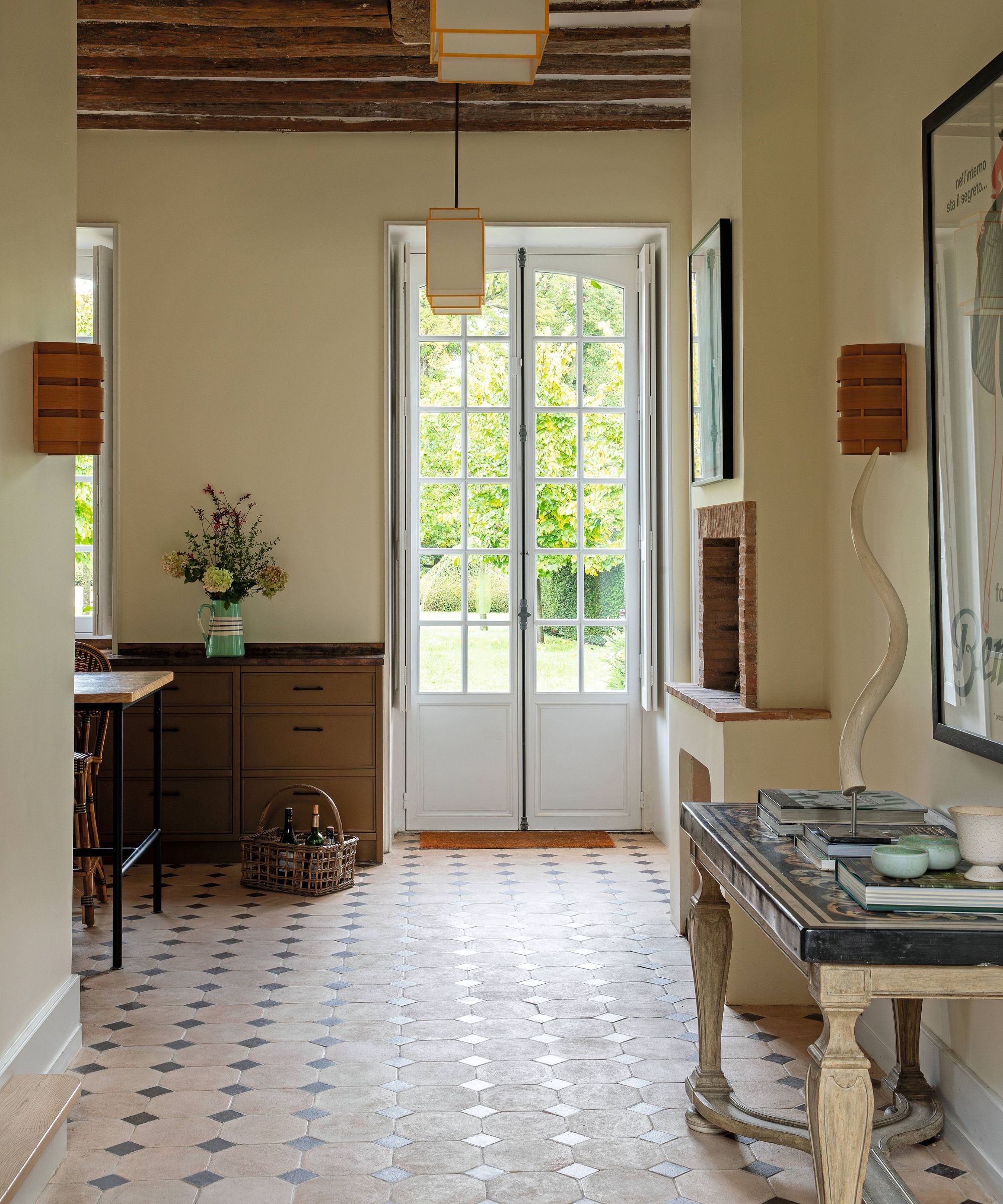 one end of a french chateau kitchen with traditional stone floor, rustic ceiling beams and french antique console table