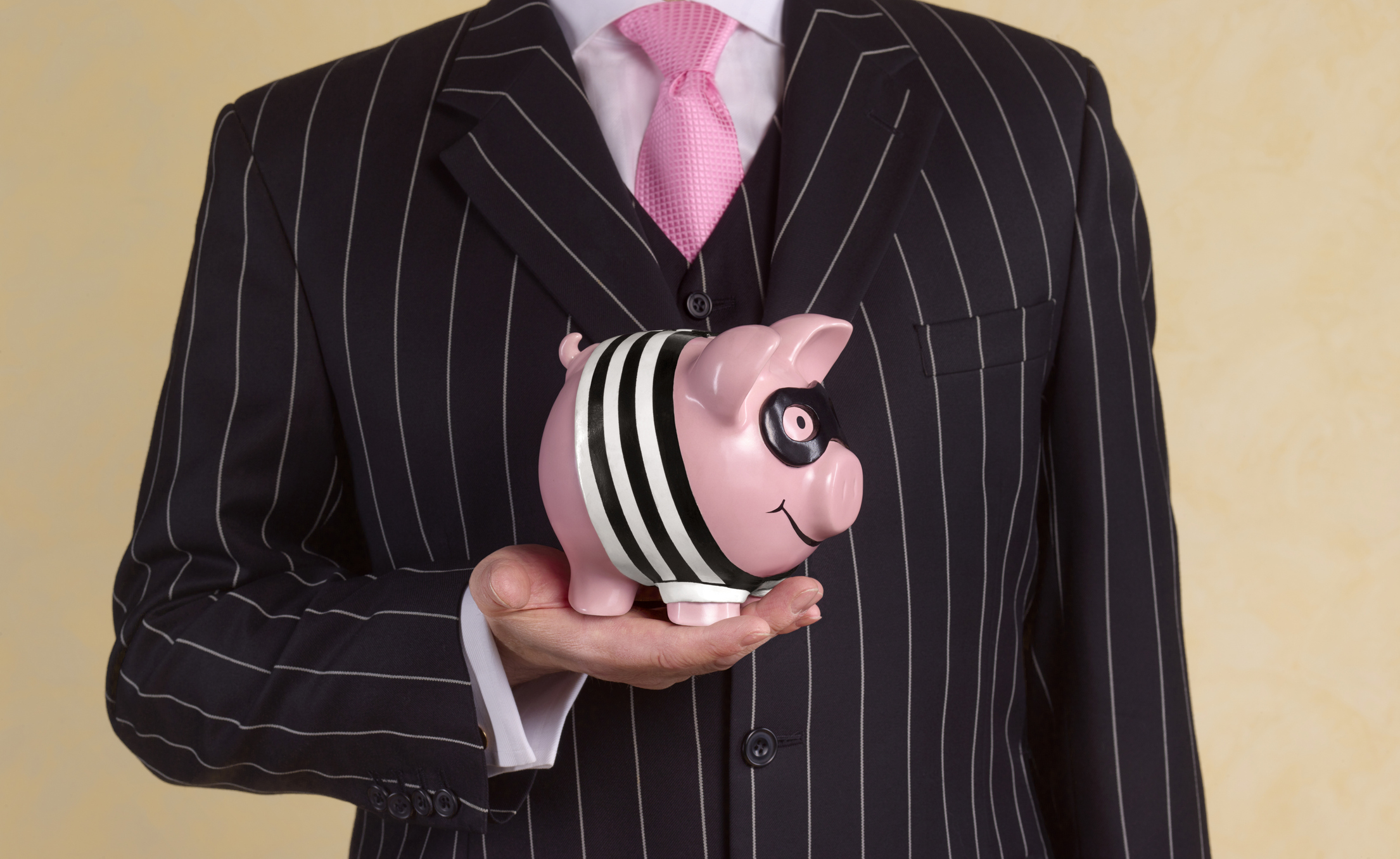 Man in a pin stripe suit holding a bank robber piggy bank