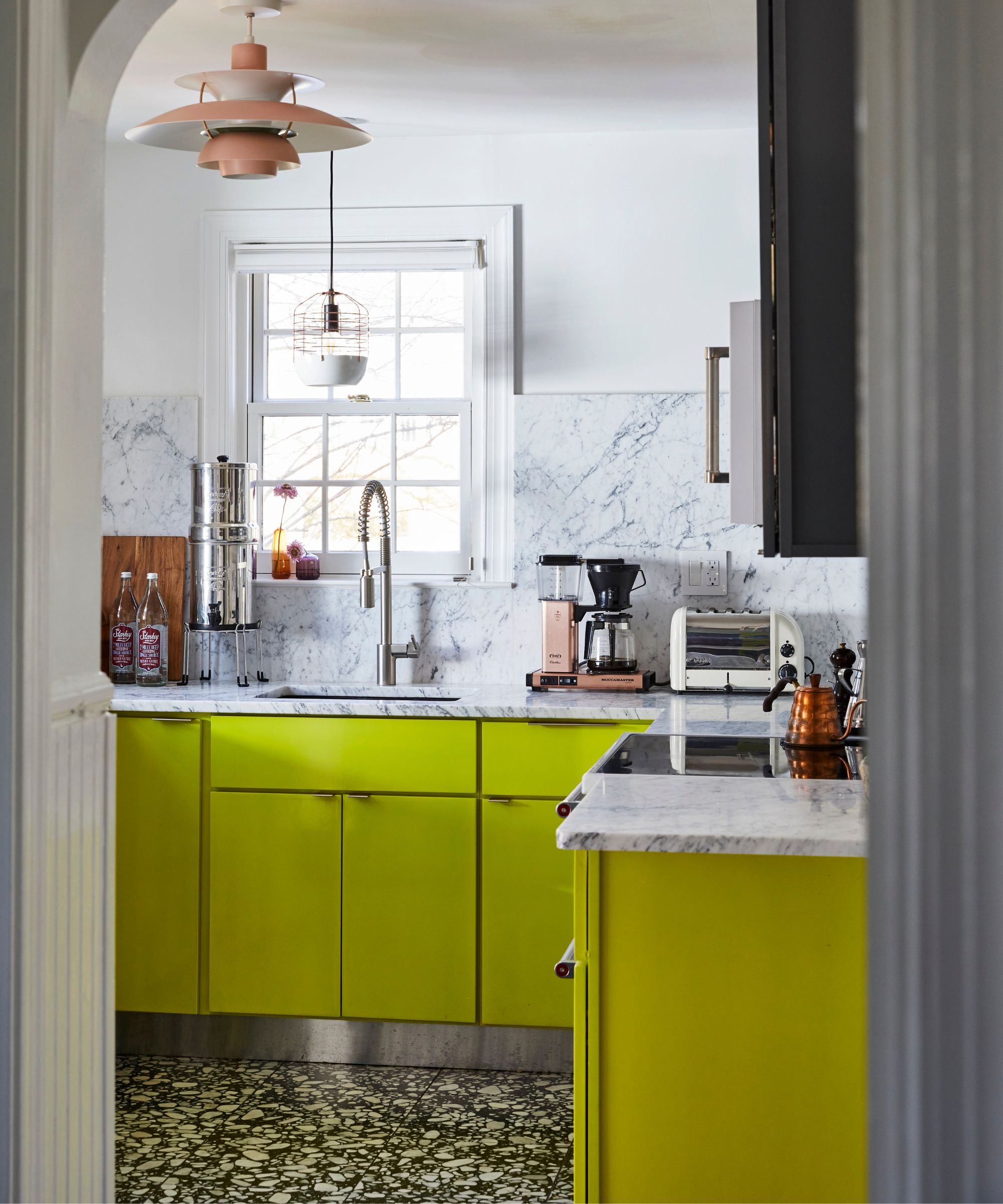 A small kitchen with white walls, a marble countersplash, and cabinets painted in Benjamin Moore's New Lime