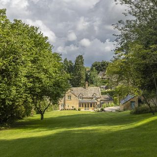 Cotswold cottage's garden with large green lawn and trees