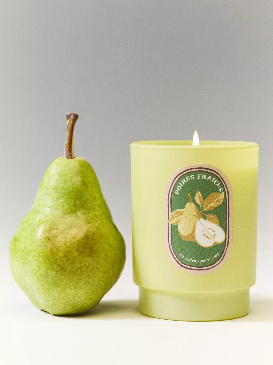 A pear candle beside a pear from Anthropologie