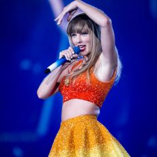 Taylor Swift onstage at the eras tour wearing a roberto cavalli crop top and colorblock skirt