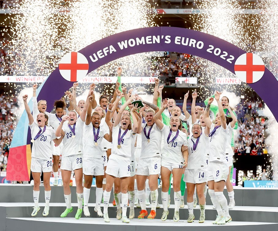 The England women's football team celebrates their victory at the UEFA Women's Euro 2022, lifting the trophy amidst confetti and fireworks.